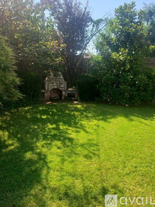 A sunny day in a lush green garden with a stone structure in the middle.