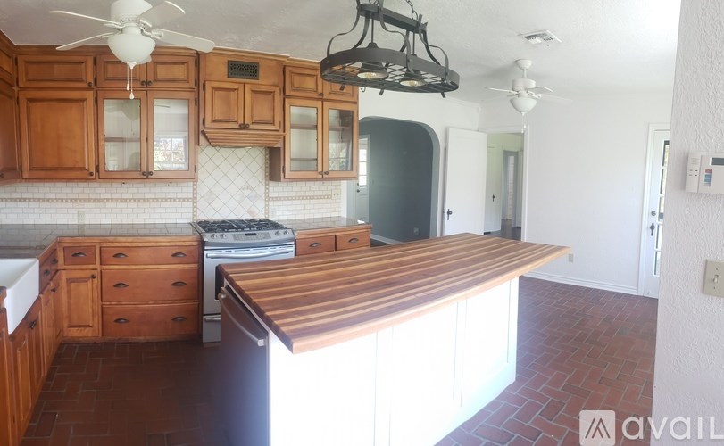 A kitchen with wooden cabinets and a brick floor.