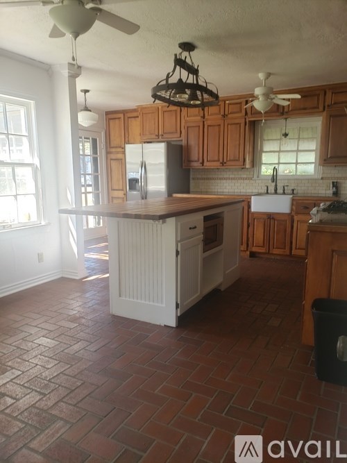 A kitchen with wooden cabinets and a brick floor.