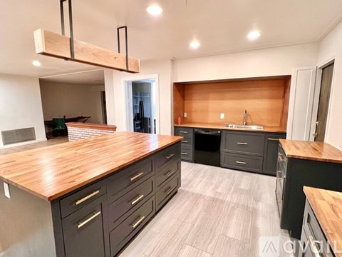 A kitchen with a wooden countertop and black cabinets.