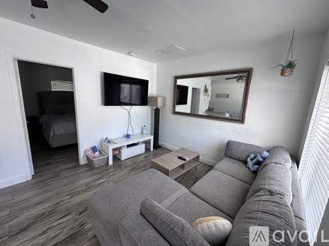 A living room with a grey couch and a television on the wall.