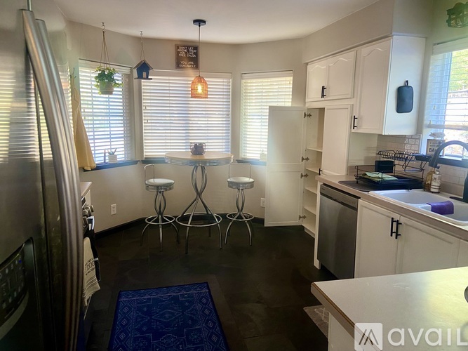 A kitchen with white cabinets and a blue rug on the floor.