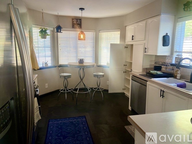 A kitchen with white cabinets and a blue rug on the floor.