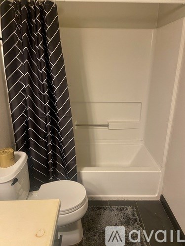 A bathroom with a toilet, a shower, and a striped shower curtain.