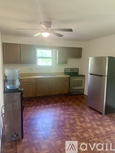 A kitchen with a refrigerator, oven, and a fan.