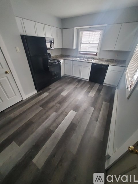A kitchen with black appliances and white cabinets.