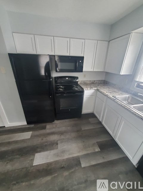 A kitchen with black appliances and white cabinets.