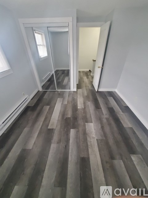 A hallway with a wooden floor and white walls.