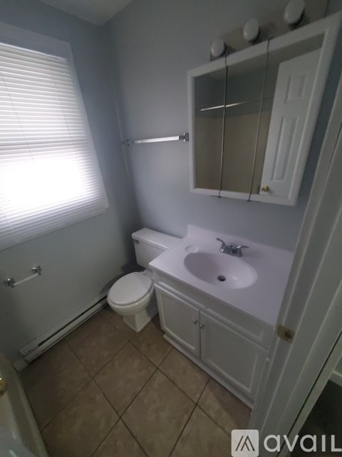 A bathroom with a toilet, sink, and mirror.