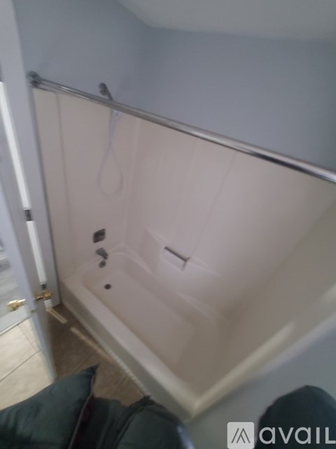 A bathroom with a white tub and a towel hanging on the door.