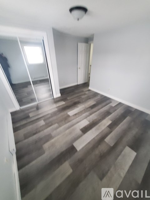 A room with wooden flooring and a white wall.