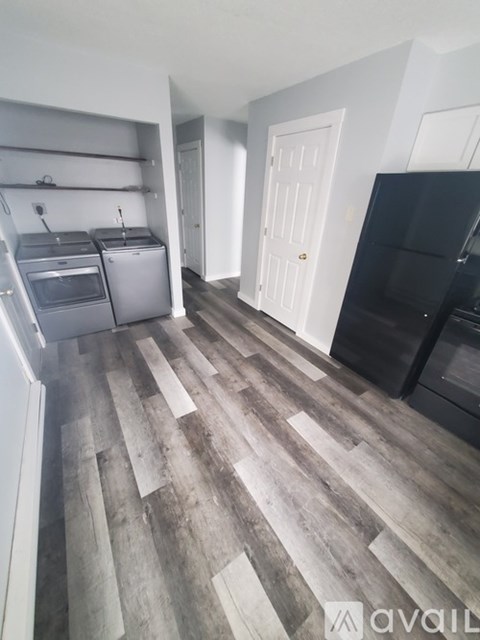 A kitchen with a black fridge and wooden flooring.