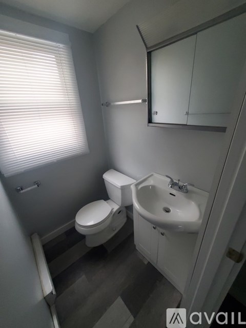 A bathroom with a toilet, sink and mirror.