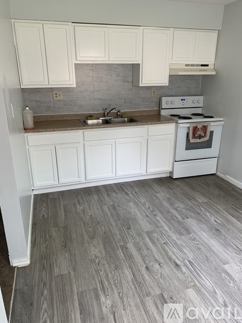 A kitchen with white cabinets and a white stove top oven.
