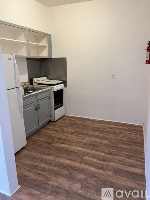 A kitchen with a white refrigerator and wooden flooring.
