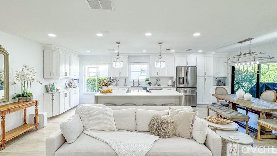 A modern kitchen with a white sofa in the foreground.