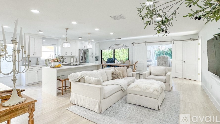 A modern living room with white furniture and a large window.