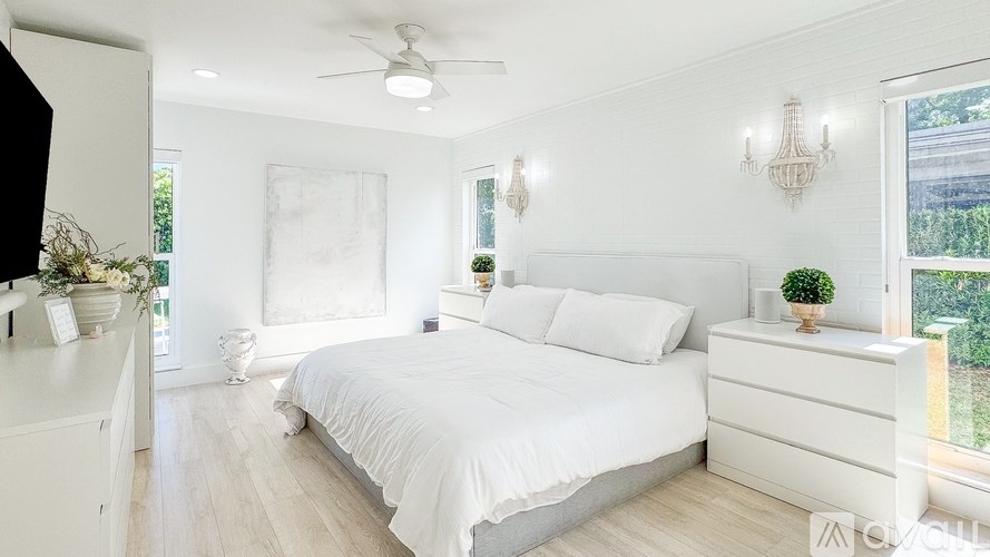 A white bedroom with a large bed and a ceiling fan.