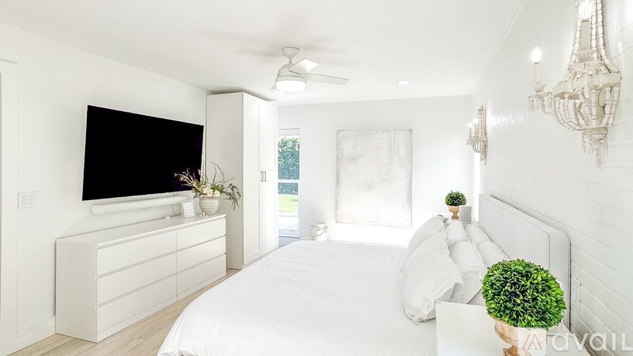 A bedroom with a large bed, a television, and a chandelier.