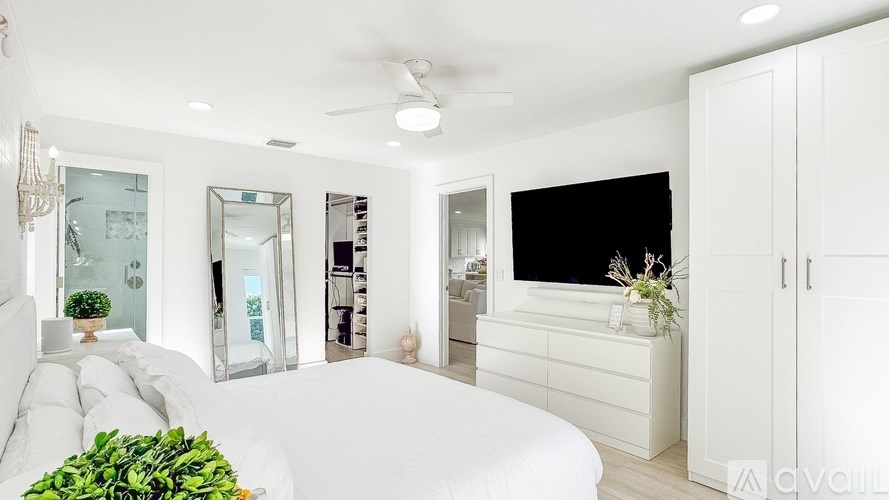 A white room with a bed and a plant.