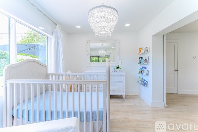 A white nursery room with a crib and a dresser.
