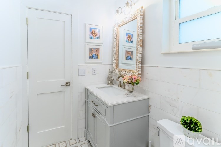 A bathroom with a white cabinet, a mirror, and a small potted plant.
