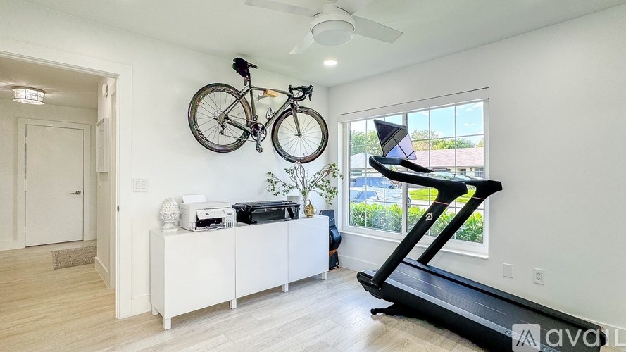A room with a treadmill, a bicycle, and a printer on a cabinet.