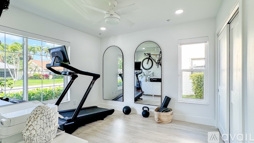 A room with a treadmill, mirror, and exercise equipment.