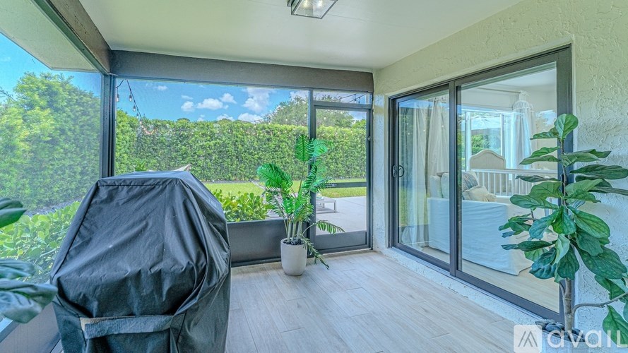 A balcony with a black chair and a potted plant.
