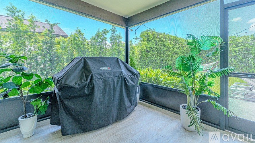 A patio with a bean bag chair covered in a black cloth and two potted plants.
