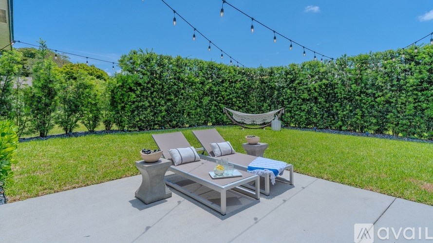 A patio with a table and chairs is set up with a hammock in the background.