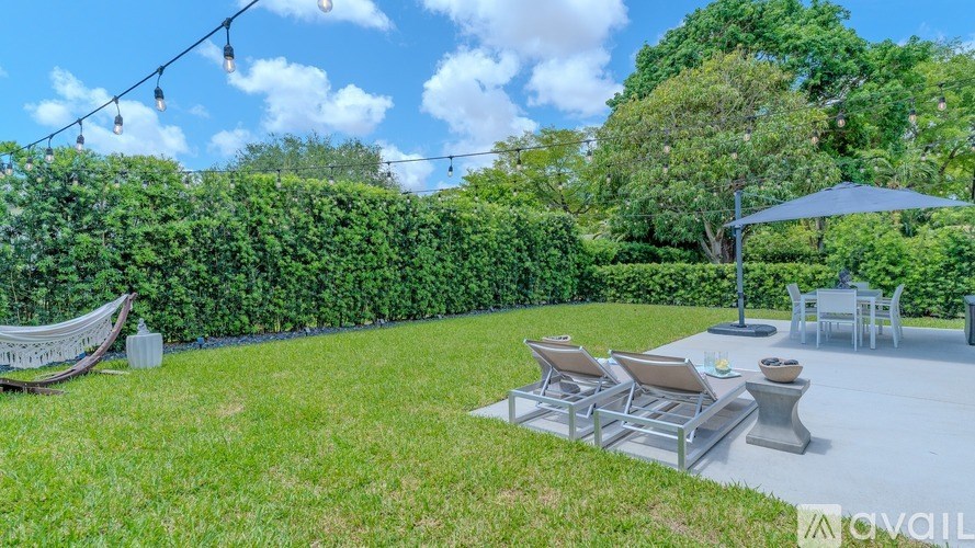A patio area with chairs and a table under a blue umbrella.