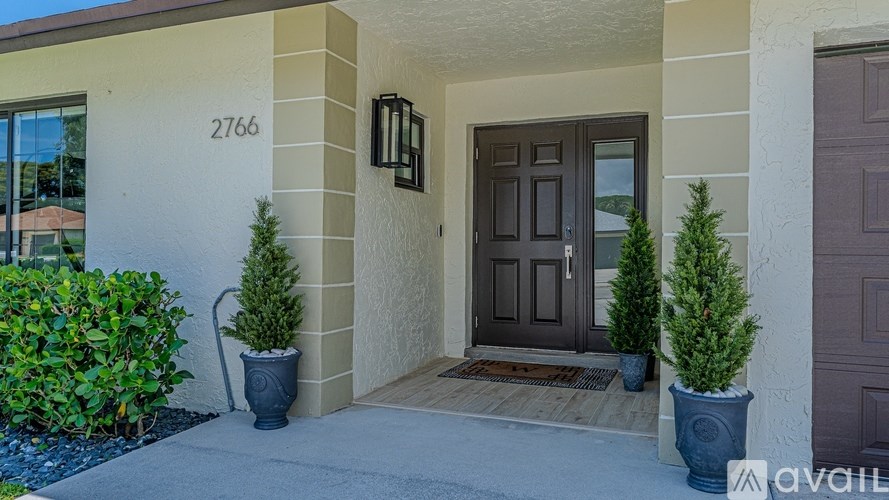 A house numbered 2766 with a brown door and two potted plants.