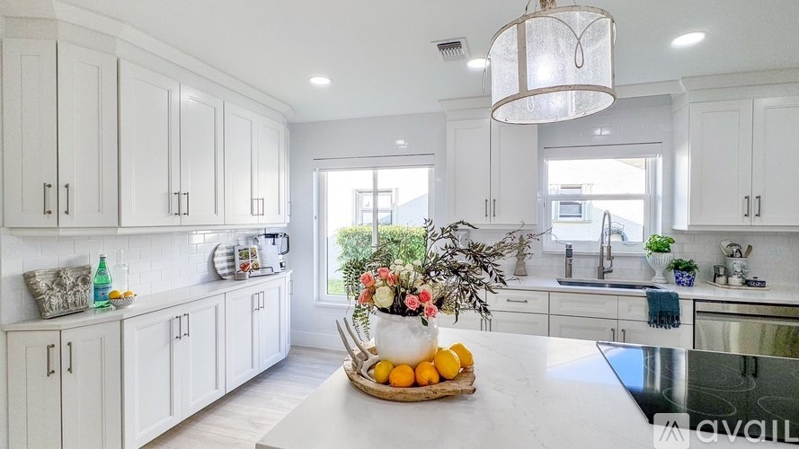 A kitchen with white cabinets and a marble countertop.