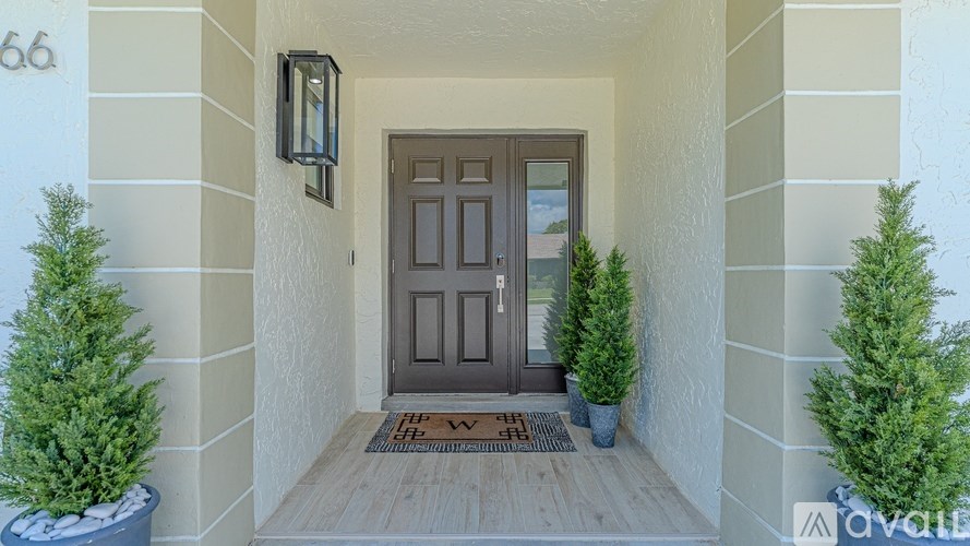 A house number 66 with a brown door and two potted plants.