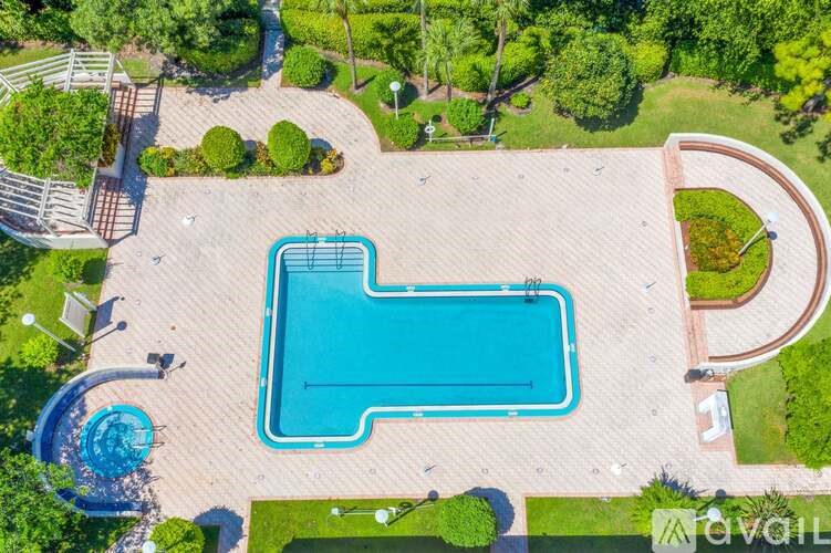 An aerial view of a swimming pool surrounded by a grassy area and trees.