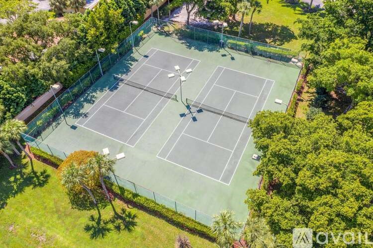 A tennis court surrounded by trees and a fence.