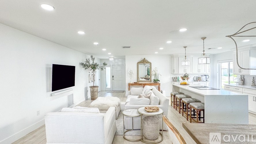 A modern living room with a white sofa and a television on the wall.