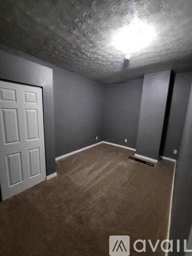 A room with a white door and carpeted floor.