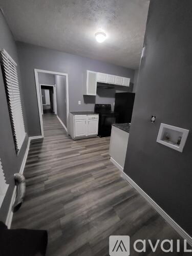 A hallway with a kitchen area on the right and a bed on the left.