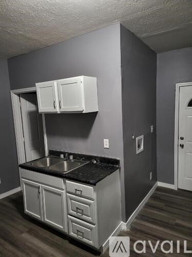 A kitchen with white cabinets and a black countertop.