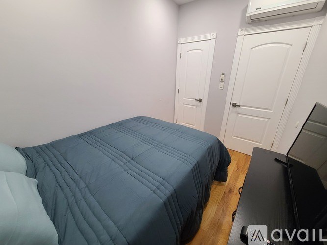 A bed with a blue comforter is in a room with two white doors.