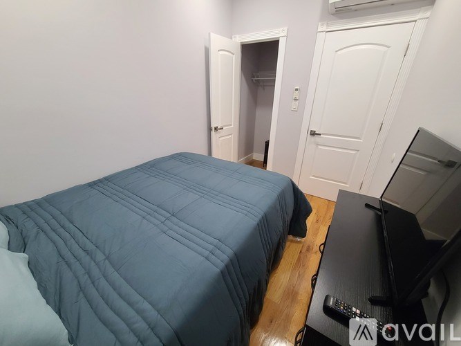 A bedroom with a bed, a TV, and a remote control.