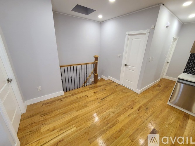 A room with wooden flooring and a staircase with a railing.