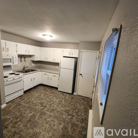 A kitchen with white appliances and cabinets.