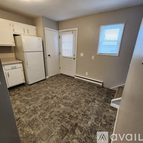 A kitchen with a refrigerator, cabinets, and a door.