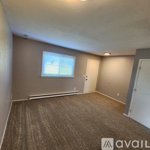 A room with a carpeted floor and a window with blinds.