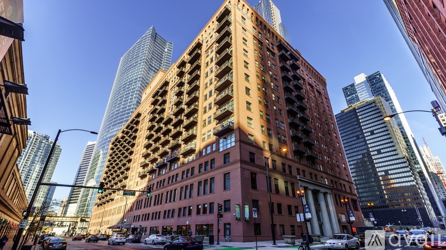 A tall red building with balconies in the middle is surrounded by other buildings.