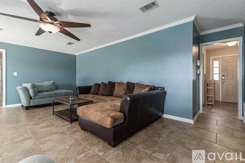 A living room with a brown couch and a ceiling fan.