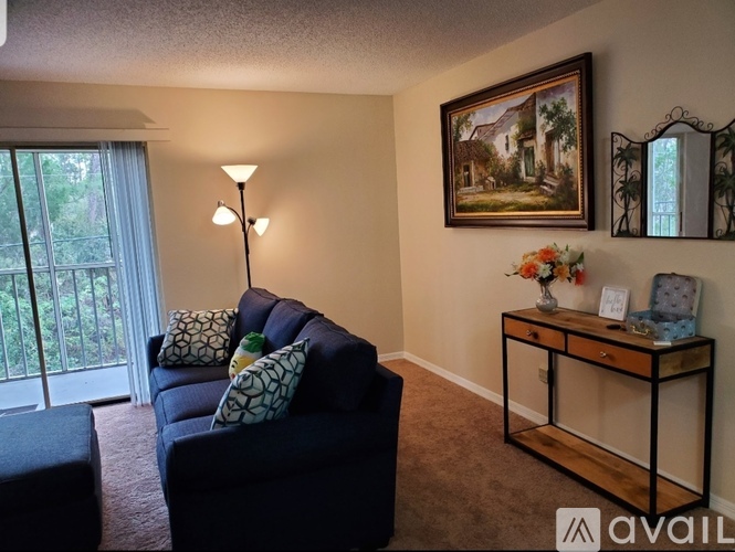 A living room with a blue couch, a lamp, a painting, and a mirror.